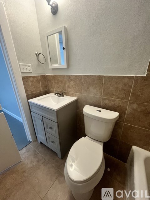 A bathroom with a toilet, sink, and a mirror.