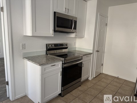 A kitchen with white cabinets and a granite countertop.