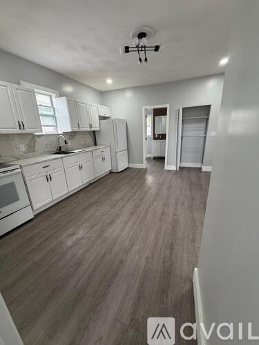 A kitchen with white cabinets and a wooden floor.