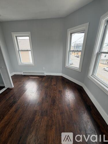 A room with wooden floors and two windows.