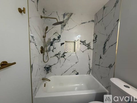 A bathroom with a marble wall and a white bathtub.