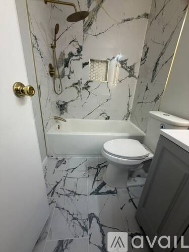 A bathroom with a marble floor and walls, a toilet, a shower, and a sink.