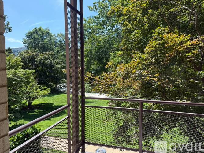 A metal fence with a view of a green lawn and trees.