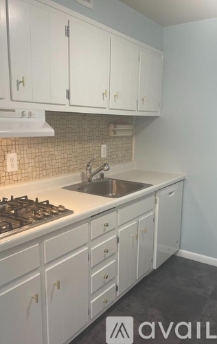 A kitchen with white cabinets and a stove top oven.