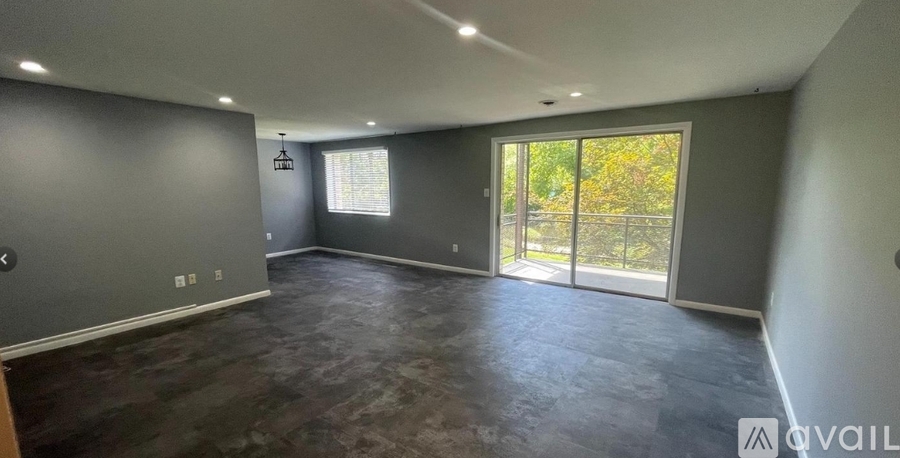 A spacious room with grey walls and a large window with sliding glass doors.