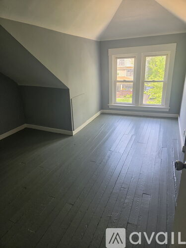 A room with a window and wooden flooring.