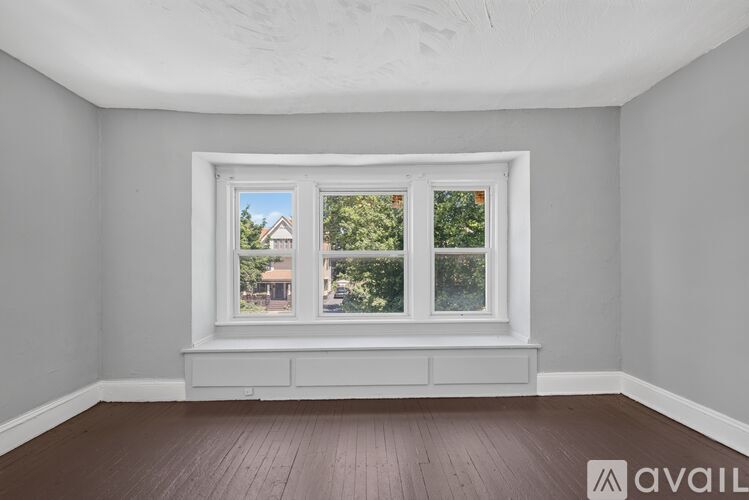 A room with a window overlooking a house and trees.