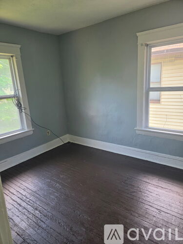 A room with wooden floors and two windows.