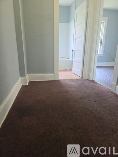 A hallway with a carpeted floor and white walls.