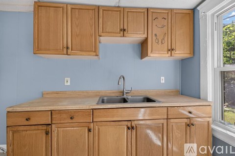 A kitchen with wooden cabinets and a blue wall.