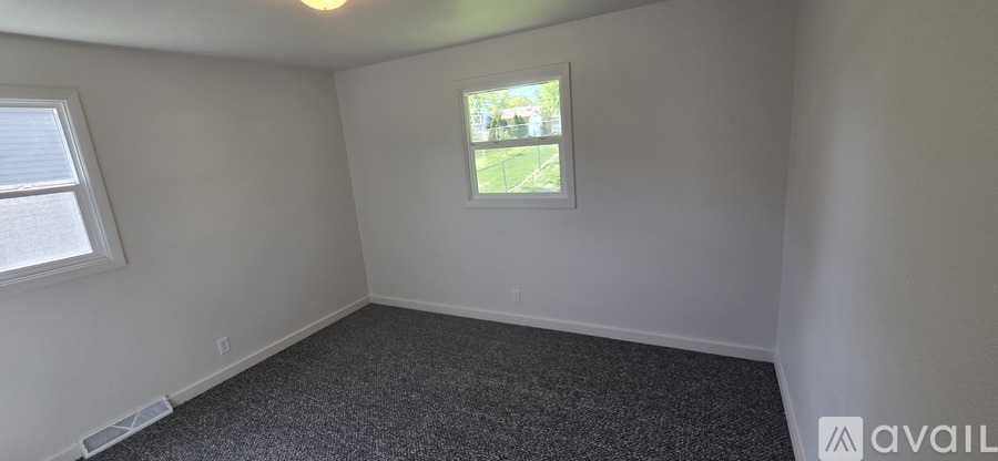 A room with a window and a carpeted floor.