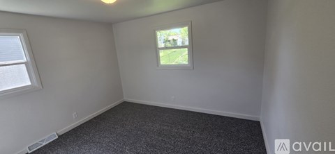 A room with a window and a carpeted floor.