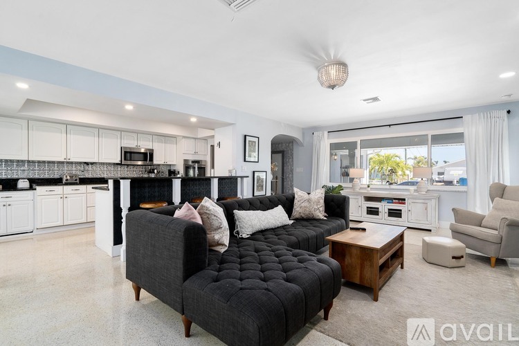 A modern living room with a black sofa and a kitchen area in the background.