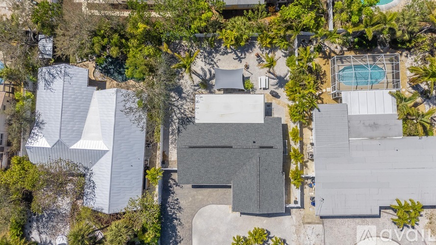 A bird's eye view of a house surrounded by trees and a pool.