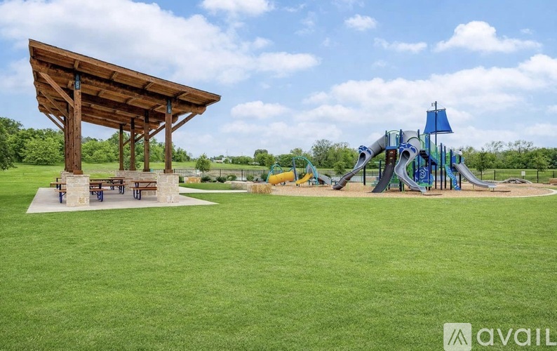 A playground with a wooden pavilion and a blue slide.