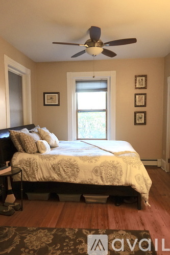A bedroom with a bed, a ceiling fan, and pictures on the wall.