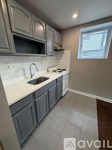 A kitchen with grey cabinets and a white countertop.