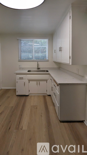 A kitchen with white cabinets and a wooden floor.