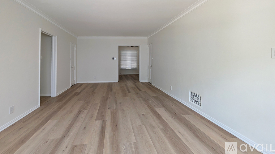 A room with wooden flooring and white walls.