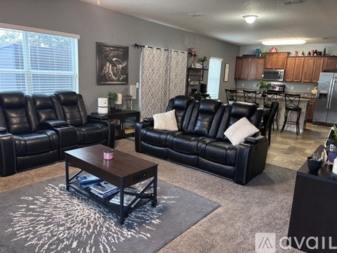 A living room with black leather furniture and a rug with white patterns.