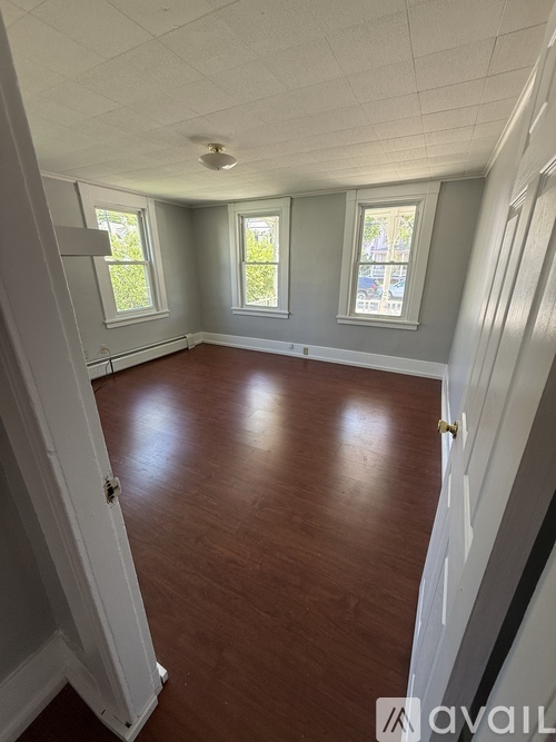 A room with wooden floors and three windows.