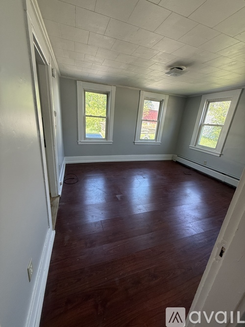 A room with wooden floors and three windows.