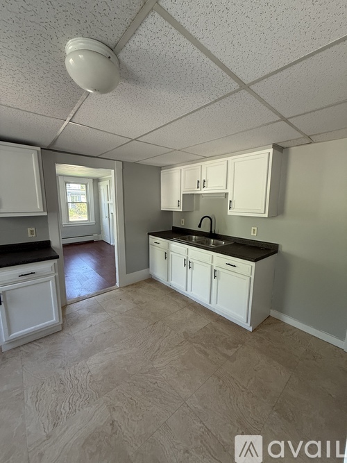 A kitchen with white cabinets and a black countertop.