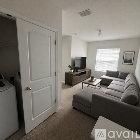 A living room with a grey couch and a television on a wooden stand.