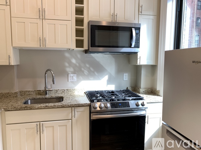 A kitchen with a stove, sink, and cabinets.