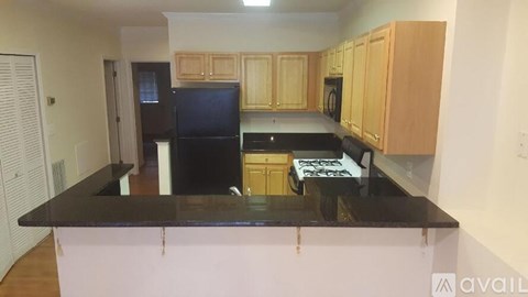 A kitchen with wooden cabinets and black countertops.