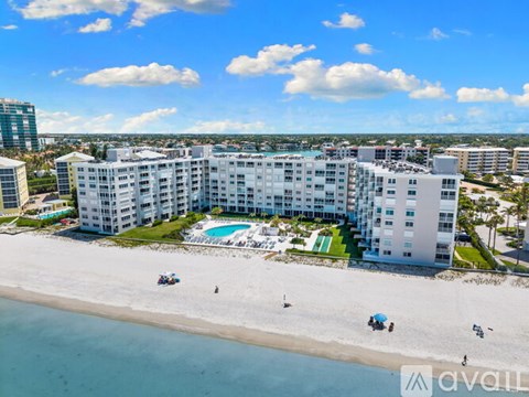 A beachfront hotel with a swimming pool and people enjoying the beach.