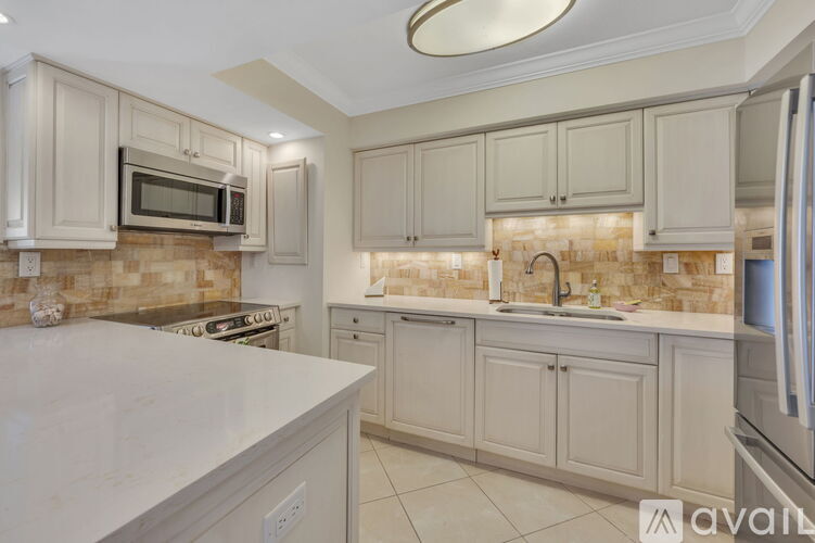 A kitchen with white cabinets and a marble countertop.