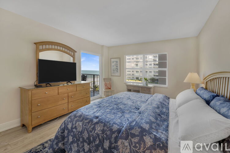 A bedroom with a large bed and a wooden dresser with a flat screen TV on top.