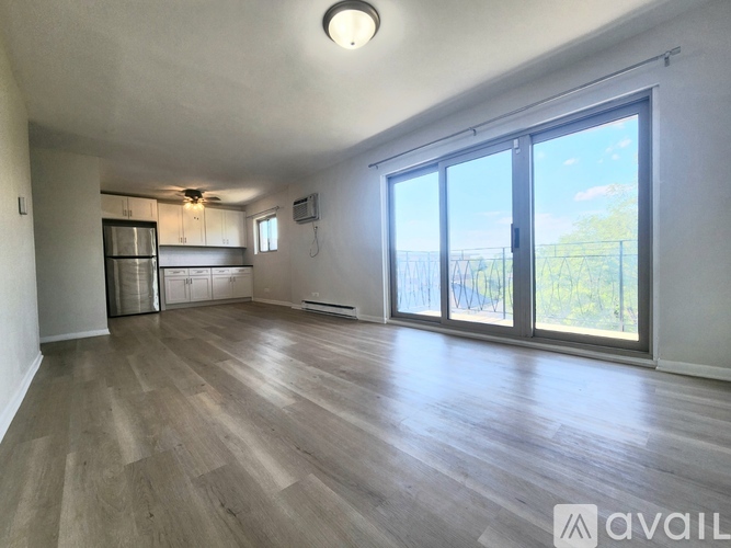 A spacious room with wooden flooring and sliding glass doors leading to a balcony.