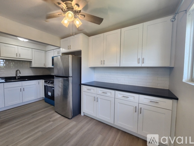 A kitchen with white cabinets and a black countertop.