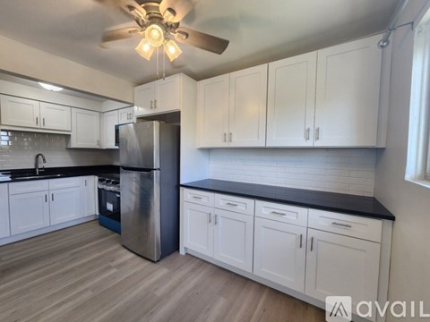 A kitchen with white cabinets and a black countertop.
