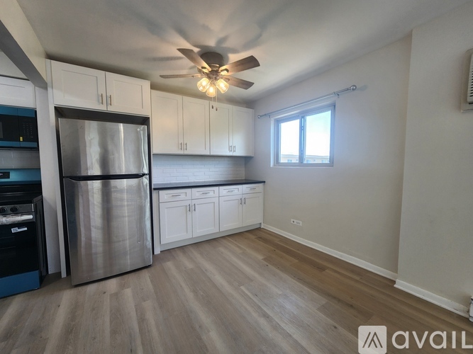 A kitchen with a refrigerator, stove, and cabinets.