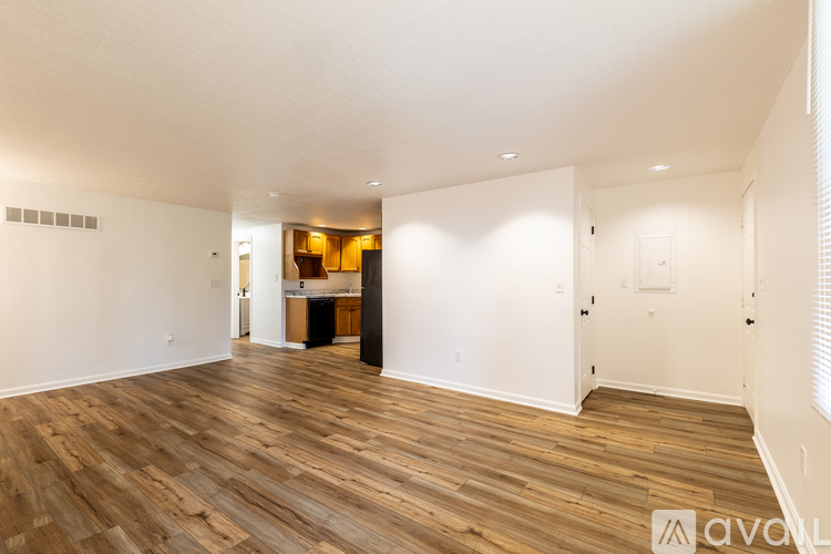 A spacious room with wooden flooring and white walls.