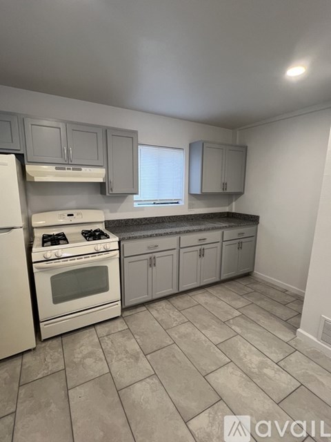 A kitchen with a white stove and cabinets.