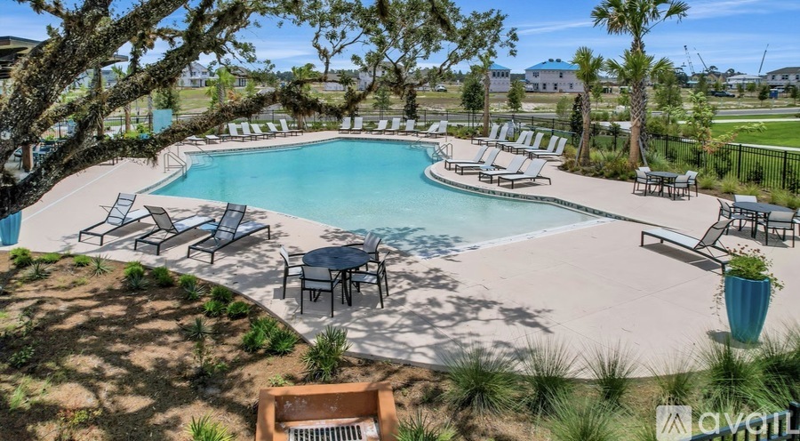 A pool surrounded by chairs and trees.