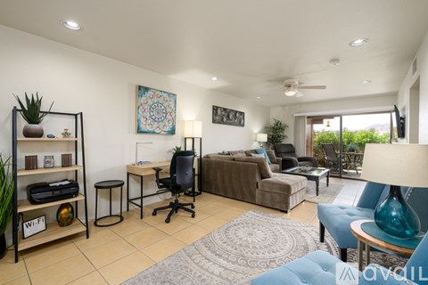A living room with a couch, chair, and a table with a lamp on it.