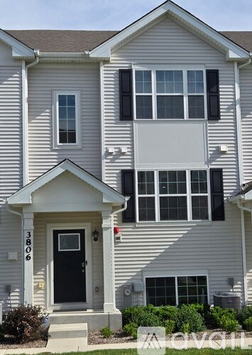 A two-story house with a grey siding exterior and a black front door.