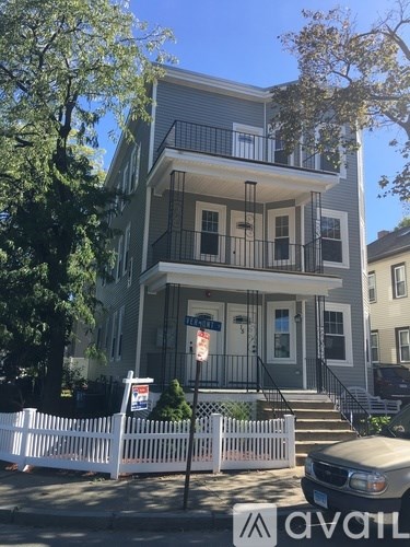 A two-story house with a white picket fence in front.