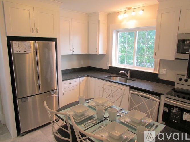 A kitchen with a refrigerator, table and chairs.
