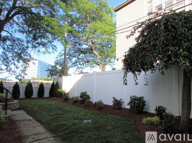 A white fence with green plants on the side.