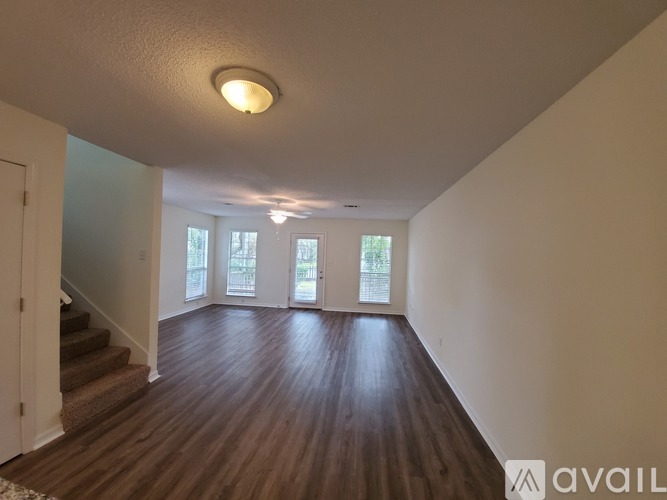 A spacious room with wooden floors and a staircase leading to the upper level.