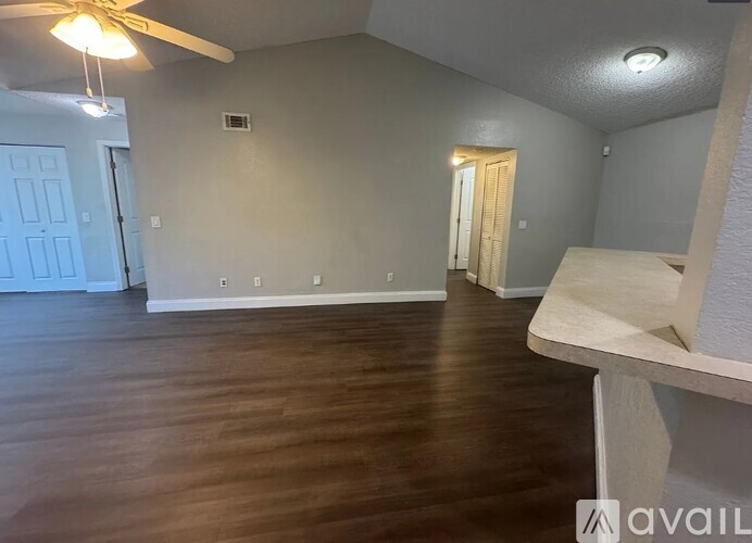 A room with a ceiling fan and wooden flooring.