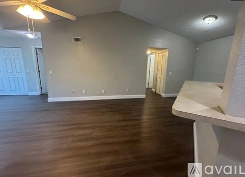 A room with a ceiling fan and wooden flooring.