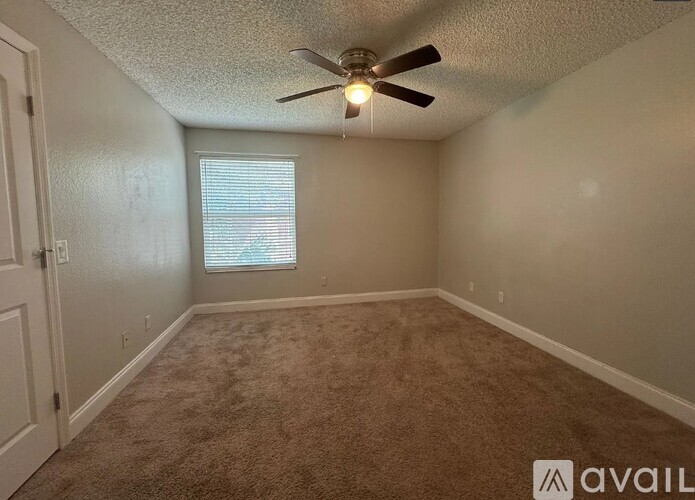 A room with a ceiling fan and carpeted floor.