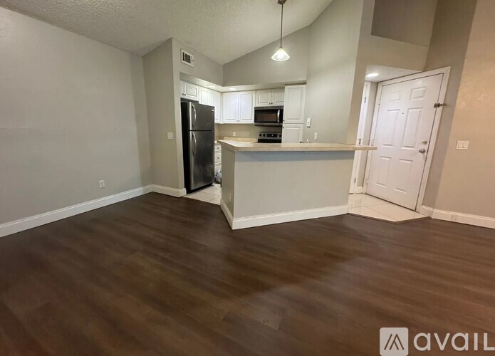 A kitchen with a black fridge and white cabinets.
